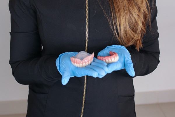 Девушка держит зубные протезы